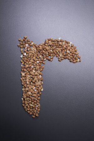 Letter r written with buckwheat On gray background, top view, copy space. Food supplies crisis, food donation on quarantine isolation periodの写真素材