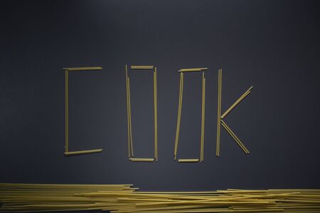 Word COOK written with spaghetti on gray background, top view, copy space. Food supplies, food donation on quarantine while coronavirus.の写真素材