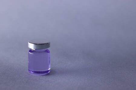 Little bottle with purple liquid on white-gray background. Isolated. Board games. Cure - medicine, vaccine. Coronavirus or covid-19 - pandemic. High quality photoの写真素材