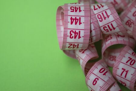 Close up of Red measuring tape on green background. Loss weight concept. Top view. Copy space....