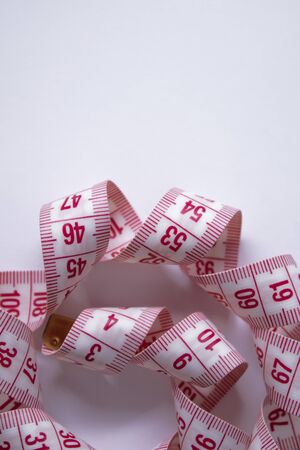 Close up of Red measuring tape on white background. Loss weight concept. Top view. Copy space. Isolated. High quality photoの写真素材
