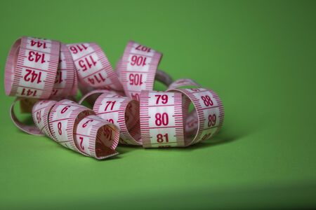 Red measuring tape on green background. Loss weight concept. Top view. Copy space. Isolated. . High...