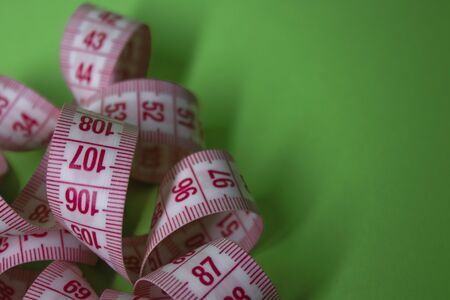 Close up of Red measuring tape on green background. Loss weight concept. Top view. Copy space. Isolated. High quality photoの写真素材