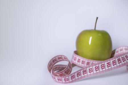 Red measuring tape over green apple. Diet and Healthy life, loss weight concept. Top view. Copy space. Isolated. White background. High quality photoの写真素材