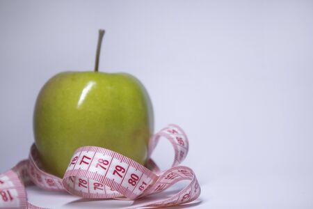 Red measuring tape over green apple. Diet and Healthy life, loss weight concept. Top view. Copy space. Isolated. White background. High quality photoの写真素材