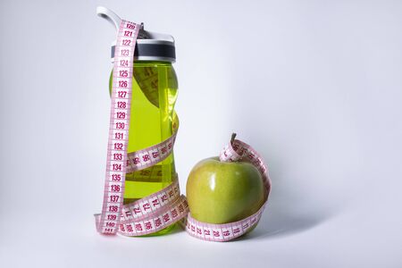Red measuring tape over green sport bottle and green apple. Diet and Healthy life, loss weight, sport concept. Top view. Copy space. Isolated. White background. High quality photoの写真素材