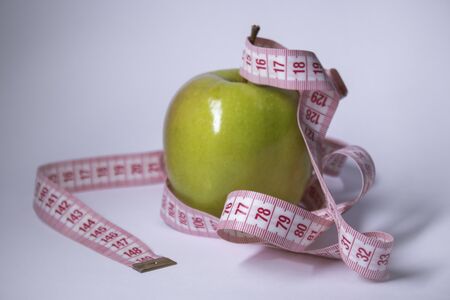 Red measuring tape over green apple. Diet and Healthy life, loss weight concept. Top view. Copy space. Isolated. White background. High quality photoの写真素材