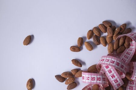 Red measuring tape with almonds . Diet and Healthy life concept. Top view. Copy space. Isolated. White background. High quality photoの写真素材