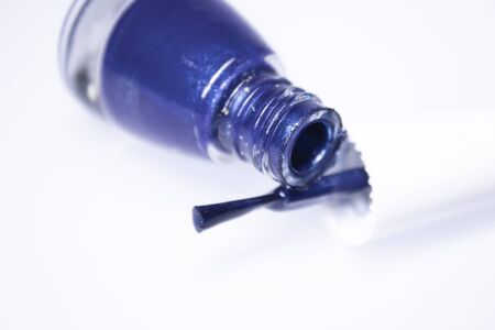 A bottle with spilled blue nail polish on white background. nail lacquer. Nail manicure concept. Isolated, copy space.の写真素材