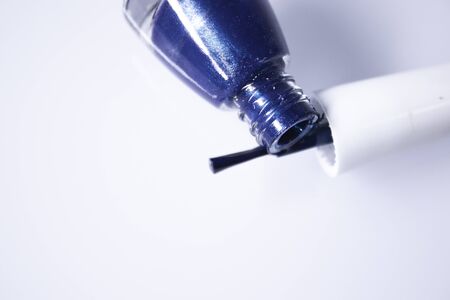 A bottle with spilled blue nail polish on white background. nail lacquer. Nail manicure concept. Isolated, copy space.の写真素材