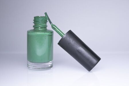 A bottle with spilled green nail polish on white background. nail lacquer. Nail manicure concept. Isolated, copy space.の写真素材
