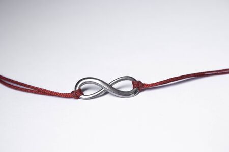 red ribbon bracelet with an infinity sign. jewelry and accessories concept. Isolated, copy space. Macro Shot. High quality photoの写真素材