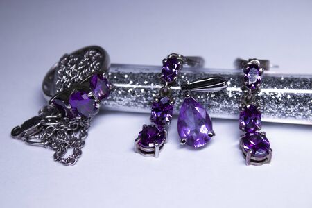 Expensive set of silver women's jewelry with violet stones - ring, pendant and earrings. Isolated, copy space. Macro Shotの写真素材