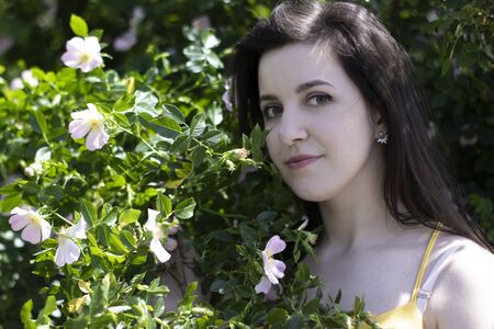 Attractive young brunette woman in yellow t-shirt. in a bush full of floweers. copy space. High quality photoの写真素材
