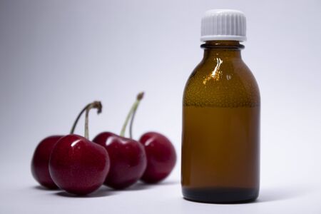 little liquid bottle with no label near cherry. body care and beauty concept. Copy space. High quality photoの写真素材