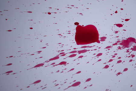 drops of red liquid - blood - on a white paper. Copy space. High quality photo