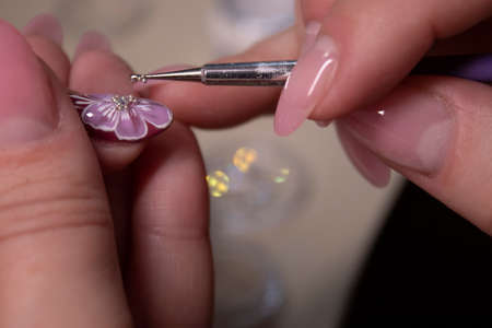 the process of doing manicure. Closeup of hands of professional manicurist, applying little stones on nails. Concept of doing manicure. beauty concept. Gel polish, shellacの写真素材