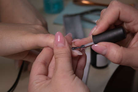 the process of doing manicure. Closeup of hands of professional manicurist, applying nail polish. Concept of doing manicure and fingernails cleaning. beauty concept. Gel polish, shellacの写真素材