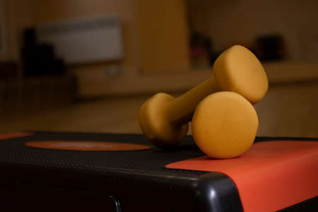 Yellow small dumbbells on the step platform in the gym. Sport concept. High quality photoの写真素材