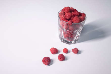 transparent glass with raspberries on white table in gray kitchen. High quality photoの写真素材