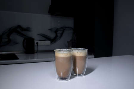 two cups of coffee in double-botoom glass on white table in gray kitchen. High quality photo