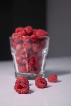 transparent glass with raspberries on white table in gray kitchen. High quality photoの写真素材