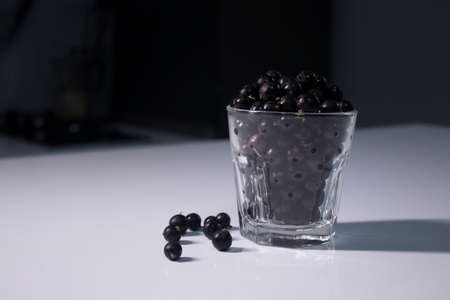 transparent glass with currants on a white table in a gray kitchen. High quality photoの写真素材