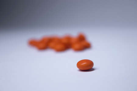 pile of orange pills on a white background. medicine and disease concept. Isolated. High quality photoの写真素材