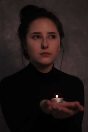 dark portrait of a sad brunette almost burst into tears holding candleの写真素材
