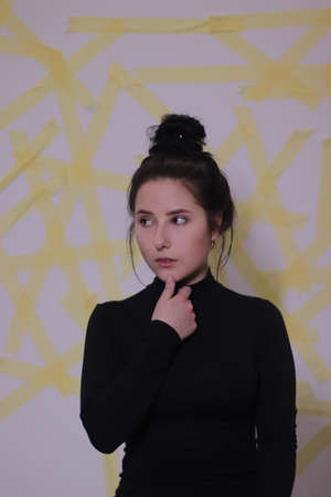 brunette in black turtleneck on background of yellow stripes on white wall