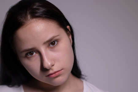 Close up portrait of pretty confident pensive thoughtful girl, looking seriously brunette. on grey...