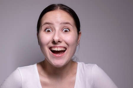 Young suprised brunette woman, isolated on gray background. happy girl actress portrait. The human emotions, facial expression conceptの写真素材