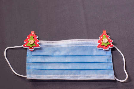 blue medical mask with christmas tree-shaped clothespins. new years medical flatly photo.