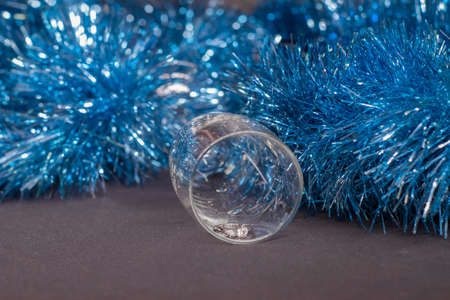 an engagement ring in a champagne glass near blue shiny tinsel for christmas tree. new years...