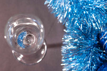 an engagement ring in a champagne glass near blue shiny tinsel for christmas tree. new years proposal theme.の写真素材
