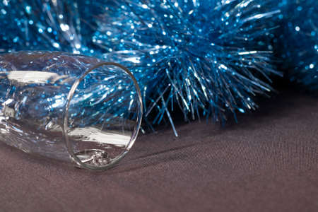 an engagement ring in a champagne glass near blue shiny tinsel for christmas tree. new years proposal theme.の写真素材