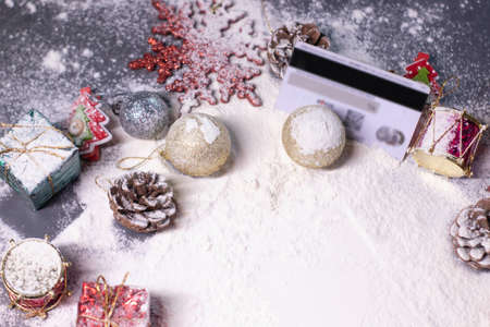 credit card next to New Years decorations in the snow. Christmas trees, balls, snowflakes, gifts,...