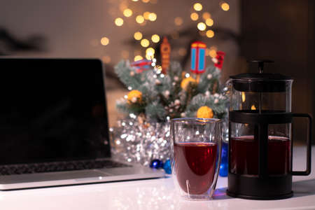 Laptop with black screen next to french press and tea near new years decorations. christmas theme...