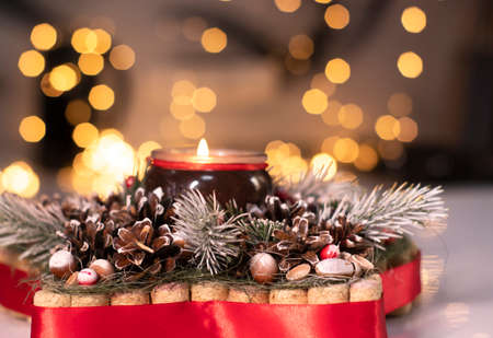 Christmas decor star-shaped made of tree branch with new years toys on it and a candle in it.