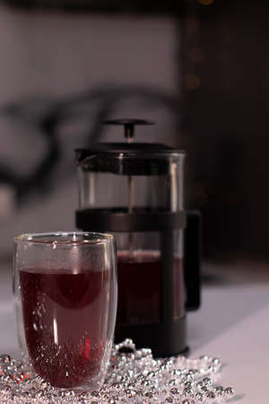 French press and tea in double-bottom glass near New Years decorations. Christmas theme.