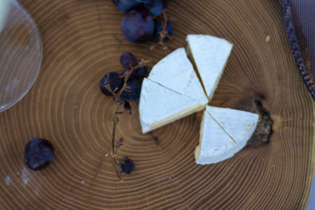 wooden stand with grapes and camembert cheese .