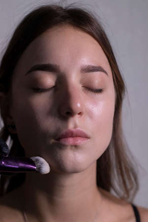 the process of applying makeup to a beautiful brunette. beauty, modeling and cosmetics concept.の写真素材