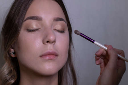the process of applying makeup to a beautiful brunette. beauty, modeling and cosmetics concept.
