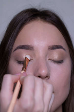 the process of applying makeup to a beautiful brunette. beauty, modeling and cosmetics concept.の写真素材