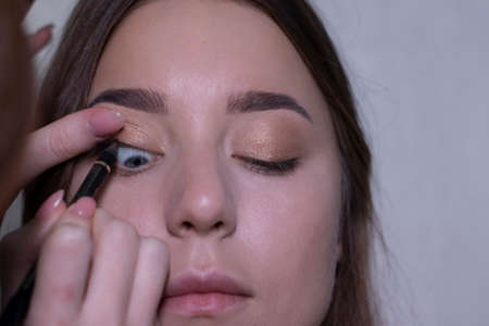 the process of applying makeup to a beautiful brunette. beauty, modeling and cosmetics concept.