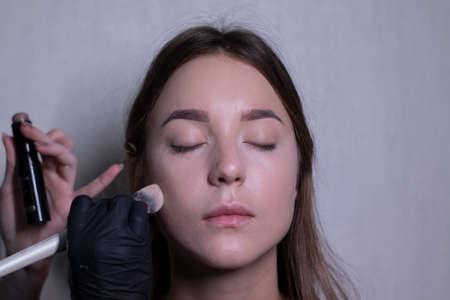 the process of applying makeup to a beautiful brunette by a master in black gloves. beauty, modeling...