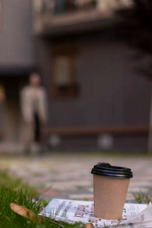 attractive slim young brunette in fashionable trench coat and black dress walking towards. autumn, yellow leaves. brick building background.の写真素材