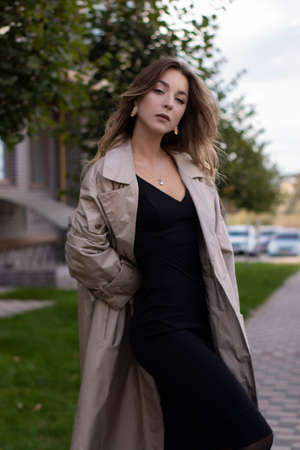 attractive slim young brunette in fashionable trench coat and black dress.の写真素材