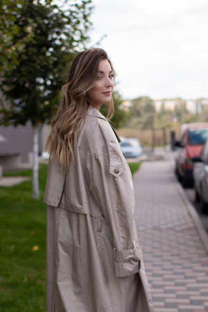 attractive slim young brunette in fashionable trench coat and black dress.の写真素材