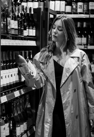 sexy attractive woman in a wine shop among shelves with wine. black and white photo. soft focus.のeditorial素材